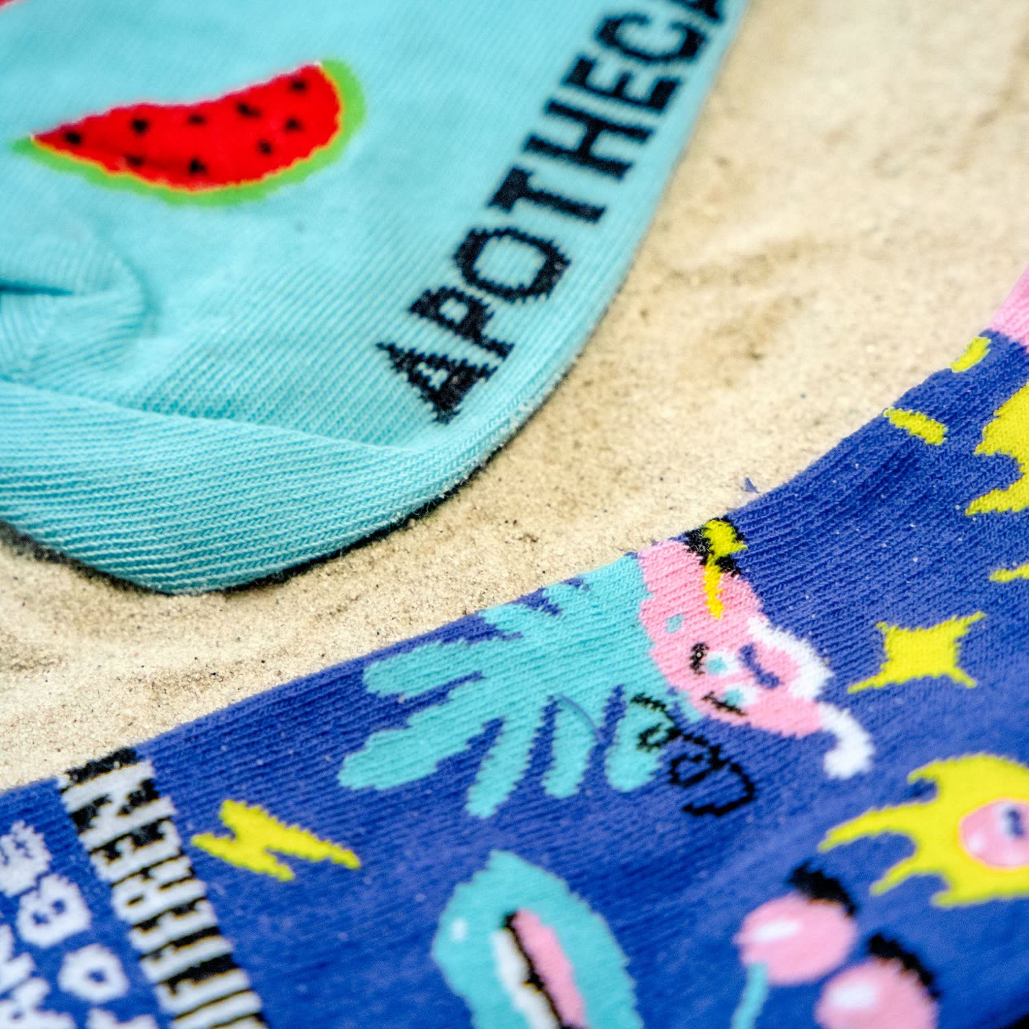 Close-up van gebrande sokken op zand met een watermeloenmotief en een all-over print