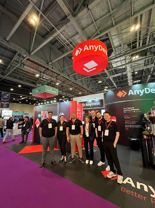 AnyDesk team at a conference event booth wearing branded merchandise